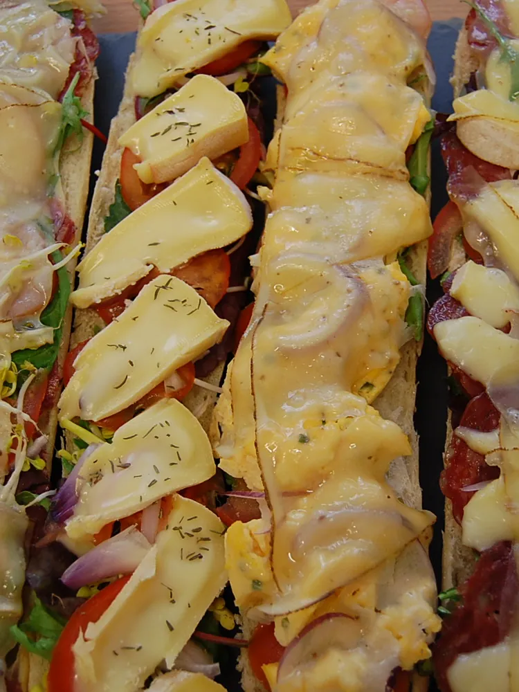 Überbackene, belegte Baguettehälften mit Käse und Schinken